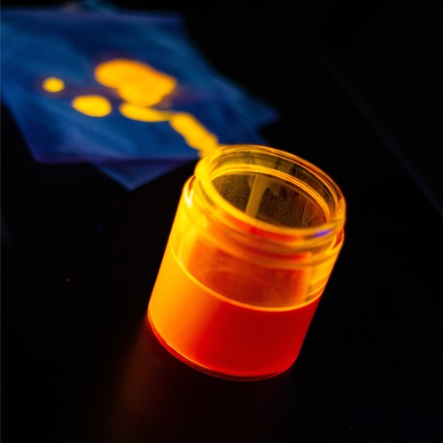 Photo of a quantum dot ink solution emitting an orange glow under ultraviolet excitation. Photo credit: UbiQD, Inc.