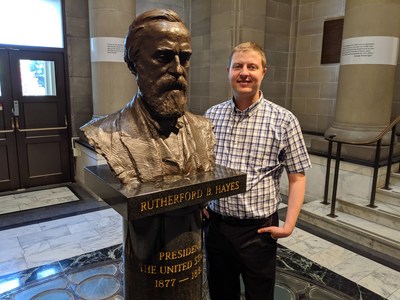 Historian Maxwell Rotbart poses with a bust of Rutherford B. Hayes during a 2019 visit to the Hayes library and museum in Fremont, Ohio.