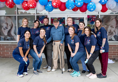 Staff members at Aspen Dental pose for a photo with patient Raymond Dumont, center, outside their office Saturday, June 11, 2022 during the 