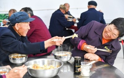 A resident tries to feed his wife, who is a bit camera shy, at a canteen for senior locals in Lichang Village of Zuoquan County, Shanxi Province, on September 18, 2022. The canteen offers free meals to villagers aged 65 and above (WEI YAO)