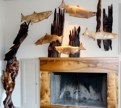 A school of salmon swim through rustic myrtlewood reeds over a fireplace shrouded with myrtlewood in an installation by Terry Woodall, an example of myrtlewood home décor at its finest.