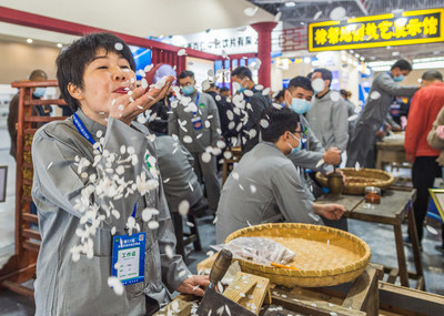 Photo shows a worker from Zhangshu Qingren TCM pieces Co., Ltd. demonstrating the traditional processing technique of Chinese herbal medicine roots of herbaceous peonies.