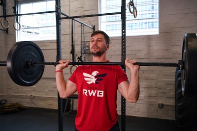 a Team Red, White & Blue member does a power clean with a barbell in a gym.