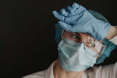 A nurse in personal protective gear wiping their forehead. (CNW Group/Unifor)