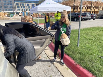 Austin, TX - Sendero Health Plans employee volunteers Cynthia Escalera (brown hat) and Briselda Herrera (black coat) load turkey and side dishes into a car at the Turkey Fest event November 12, 2022 at the East Austin Neighborhood Center. The event was sponsored by Sendero Health Plans, the Neighborhood Services Unit of Austin Public Health and the Watershed Protection Department of the city of Austin with donations from the Central Texas Food Bank. Photo credit: Sendero Health Plans
