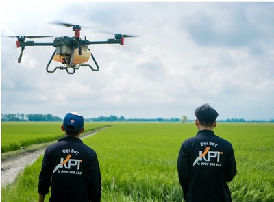 Drone pilots stood beside a rice paddy to operate drones for spraying