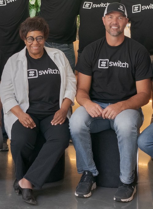 Kathy Roberts, CEO de Switch Reward Card sentada con Bradley Willden, COO/Presidente de Switch Reward Card y su equipo.