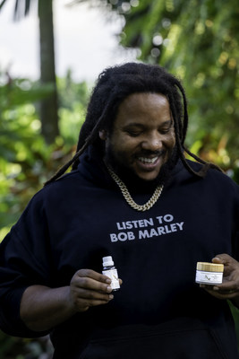 Kx Family Care Founder, Stephen Marley, pictured with the Hair and Beard Oil and Pain Relief Balm from the brand's Limited Edition Kx Holiday Bundle.