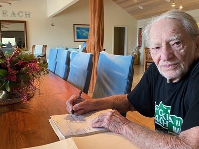 Willie Nelson signing 2022 Farm Aid grant checks.