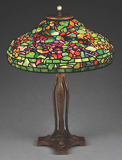 Exquisite signed/numbered Tiffany Studios Nasturtium table lamp with 19in (dia.) leaded-glass shade featuring multicolored confetti glass tiles and flowers in various shades of red, orange, purple and yellow against a green ground. Tiffany-stamped telescoping cat's-paw base. Excellent condition. Estimate $120,000-$160,000