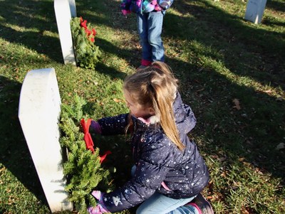 Youth volunteer places a veteran's wreath on National Wreaths Across America Day.