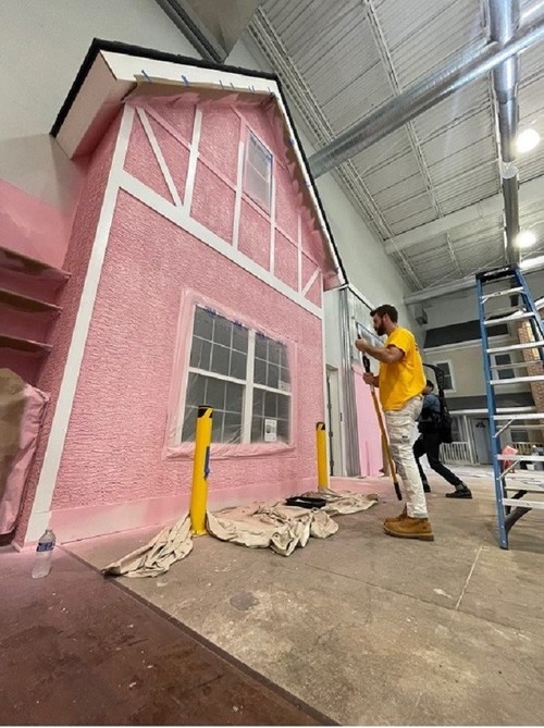 สมาชิกในทีม CertaPro Painters® ทาสีสถานที่ฝึกอบรม CertaCity สีชมพูสำหรับแคมเปญ Paint It Pink ประจำปี