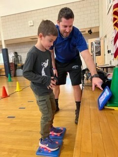 Bristol Public Schools PE teacher shows student the code that is powering the game he's playing with Unruly Splats.