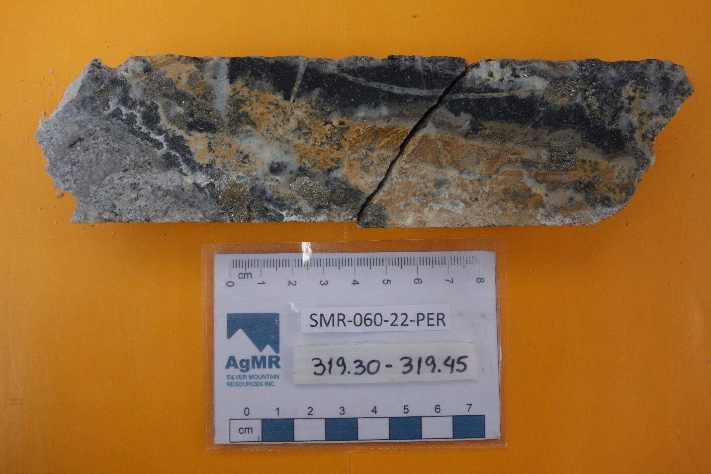 Fig.2: Photo of mineralized interval of drill core, Perseguida vein, hole SMR-060-22-PER, 319.30 – 319.45 m depth. Vein interval is composed of several generations of grey and milky white quartz, with irregular pods and fine veinlets of silver sulpho-salts, galena, sphalerite, chalcopyrite and pyrite. Late rhodochrosite with interspersed brown iron oxides is also visible. (CNW Group/Silver Mountain Resources Inc.)