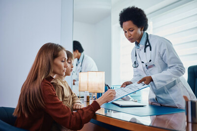 Mother holds child while signing healthcare paperwork as the responsible party for service charges