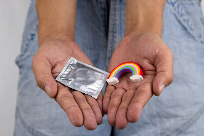 Hands holding a condom and rainbow eraser