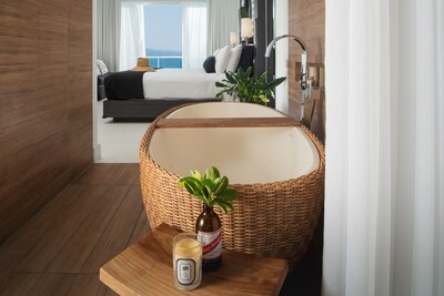 A wicker-wrapped oval tub plays center stage between the bathroom and guest room at S Hotel Jamaica