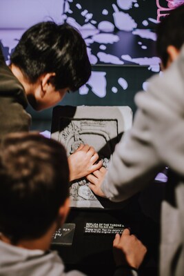 Guests touch a 3D replica model of a stone panel.