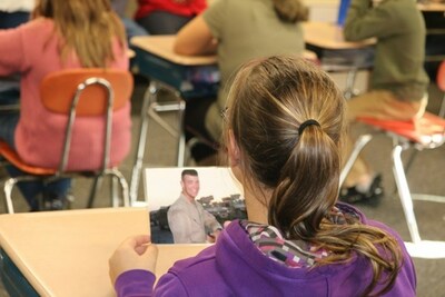 A student holds a photo of fallen Marine, Cpl. Daniel Lee Tatum, while learning from his mother.
