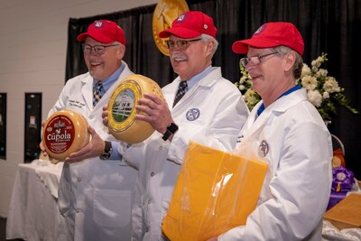 From Left: U.S. Championship Cheese Contest Assistant Chief Judge Tim Czmowski holds the First Runner-Up, Vintage Cupola American Original Cheese by Red Barn Family Farms in Appleton, Wisconsin; Chief Judge Jim Mueller holds the 2023 U.S. Champion, Europa by Arethusa Family Farms in Bantam, Connecticut; and Director of Logistics Randy Swensen holds Second Runner-Up, a Medium Cheddar by Associated Milk Producers Inc. in Blair, Wisconsin.