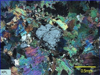 Figure 6: Thin section photographs of sample GM10403 taken with polarized light (crossed polars). Coloured grains are zinnwaldite, large grey central grain is topaz. Note that this photo is not intended to be representative of broader mineralization on the Project. (CNW Group/TinOne Resources Corp.)