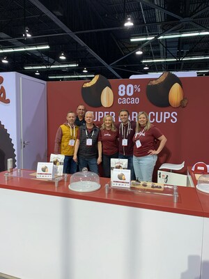 Justin's team members showcasing Justin's® Super Dark Chocolate Peanut Butter Cup and Super Dark Chocolate Espresso Almond Butter Cup.