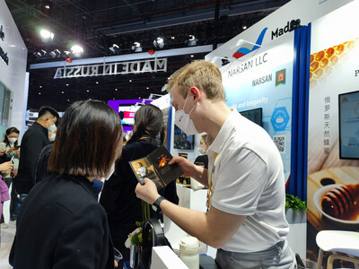 An exhibitor (right) introduces products to visitors at his booth during the fifth China International Import Expo.