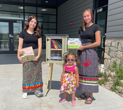 White Earth Nation members Lila Berry (left) and Hannah Otto (right) with a young reader at a Little Free Library granted through the Indigenous Library Program, outside the White Earth Indian Health Services building.