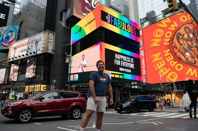 Owin Pierson posing in front of his billboard for OUTFRONT's "15 Seconds of Fabulous" PRIDE month campaign.