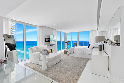 Floor-to-ceiling windows in the primary suite allow for beautiful ocean views and ample natural light. Sliding glass doors open to one of the private terraces. MiamiLuxuryAuction.com.