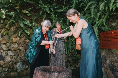 Elyn MacInnis y su hija usan un balde para extraer agua de un pozo centenario en Kuliang. Fotografía de Weng Rongfei). (PRNewsfoto/People's Daily)