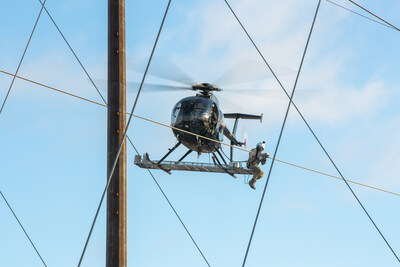 A PPL Electric Utilities employee installs a Dynamic Line Rating (DLR) sensor onto a transmission line from a helicopter.