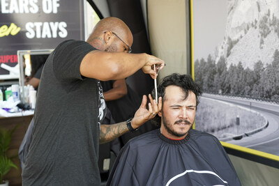 Celebrating nearly 50 years of super stays with Super 8, truck driver Collin Duran, right, of Sioux Falls S.D. gets a fresh new look by stylist Anthony Johnson during a pit stop at the brand’s pop-up salon on Tuesday, August 8, 2023 in Summit, S.D. (Craig Lassig/AP Images for Super 8 ® by Wyndham)