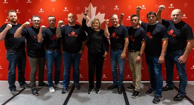 The Unifor D3 Auto Bargaining Committee raise their fists in the air with the Unifor red backdrop behind them. (CNW Group/Unifor)