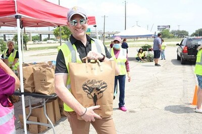 Volunteers at the San Antonio Military and Veteran Food Distribution hold bags of groceries before loading into the cars of attending Veterans.
