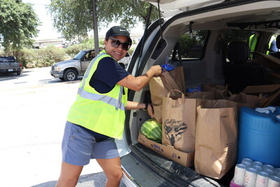 Volunteers load bags of groceries into the car of an attending Veteran.