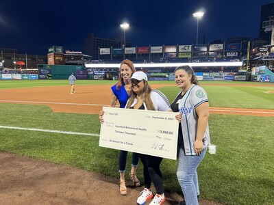 Jen Collier, president of Health and Risk Solutions, Sun Life U.S. presents donation to Monica Diaz, chief executive officer of Hartford Behavioral Health, at last Friday's Yard Goats game