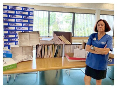 MNA President Katie Murphy, RN, standing in front of the unsafe staffing forms filed by nurses across Massachusetts between January 2022 and July 2023.