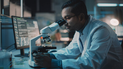 Photo of a medical researcher looking through a microscope