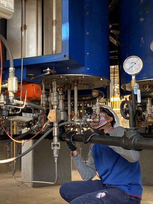 A worker installs an ultra-low-NOx hydrogen-powered industrial burner prototype for use in high-heat processes