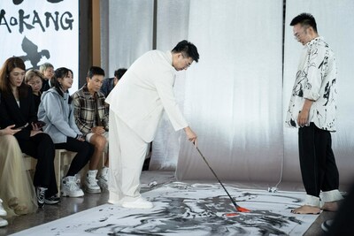 Wang Chen, vice president of Aokang,writes the eyes of a dragon painted by Chinesecalligrapher artist Zhu Jingyi at the fashion show