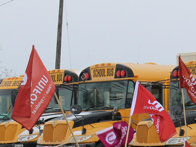 School buses are parked together with Unifor flags. (CNW Group/Unifor)