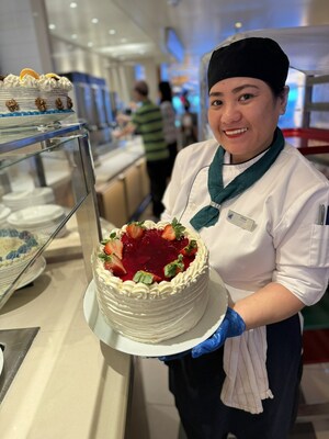 Assistant Pastry Chef Desa showcases one of many cakes available at Holland America Line's 'Cake Me Away' celebration in Lido Market. Debuting on board in time for National Cake Day Nov. 26, Cake Me Away displays more than 22 tantalizing five-layer cakes in 16 decadent flavors, with extra servings of the most popular types.