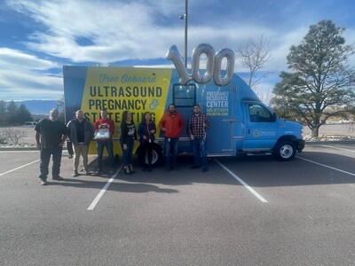 Save the Storks staff celebrate and stand in front of the 100th Stork Bus, a state-of-the-art mobile medical clinic.