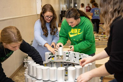 Club members, Kaitlyn Moore (left) and Charley Halford (right), help build Omega Chi's "Can It Up!" entry using donated cans of food.
