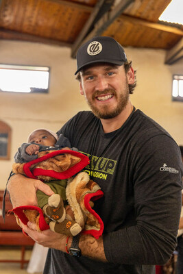 Bradley Pinion holds a baby at a Compassion survival center in Tanzania.