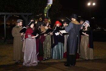 Students in Dickens-era attire serenade visitors with Christmas carols.
