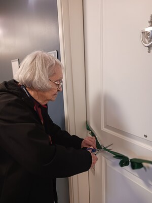 Resident cutting the ribbon for her new apartment
