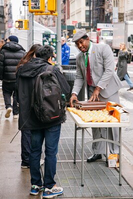 Lionel Boyce offering a Daiya's dupe grilled cheese sandwich to the passersby in character
