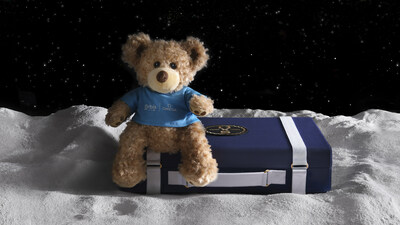 The MoonSwatch Moonshine Gold suitcase is one of 11 to be auctioned by OMEGA for global eye care nonprofit Orbis International. Pictured with the suitcase is Seymour the Bear, a friendly companion provided to young patients undergoing eye surgery.